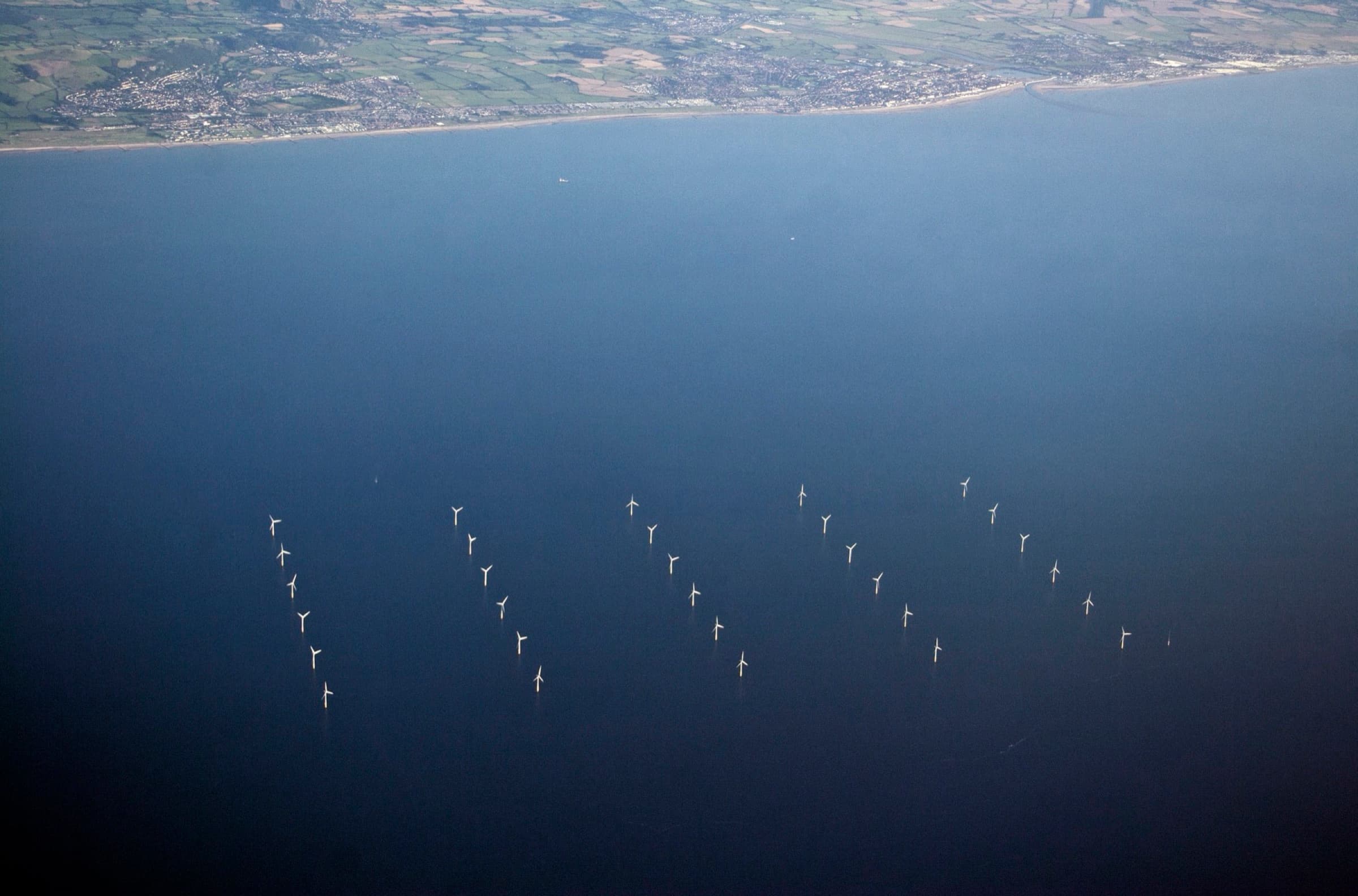 Aerial view of an offshore wind farm off a coastline